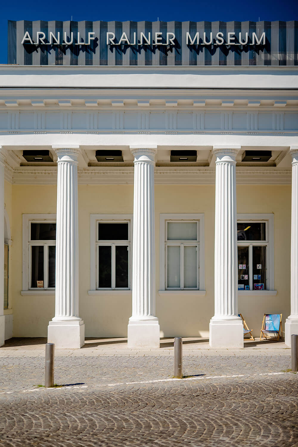Helle Fassade des Arnulf Rainer Museums in Baden mit mehreren Säulen vor dem Eingang.