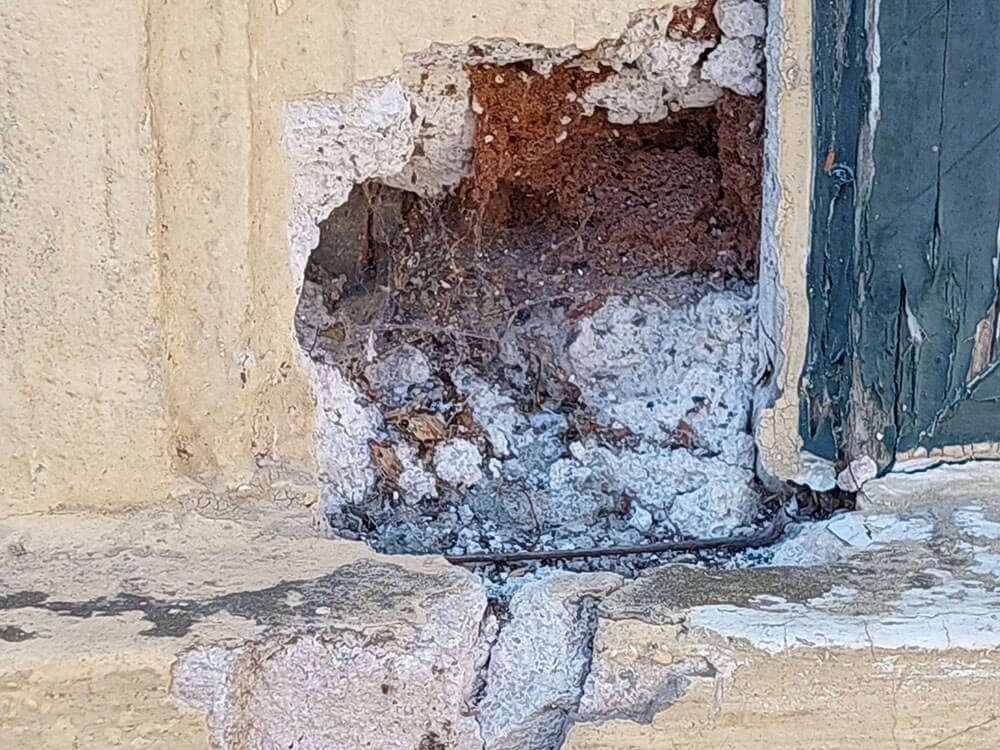 Nahaufnahme einer Mauer mit heller Fassade. Abbröckelnder Putz.