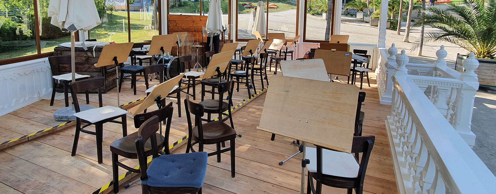 Seitlicher Blick in den Musikpavillon mit aufgestellten Stühlen und Notenständern im leeren Innenraum.